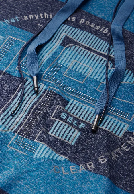Nahaufnahme eines blauen Hoodies mit dekorativem Muster und glänzenden Details.